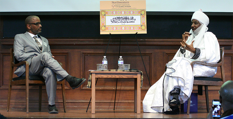 two men seated on a stage